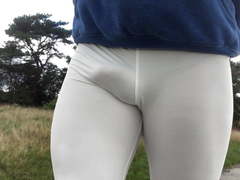 Public outdoor walk in white leggings and black boots .